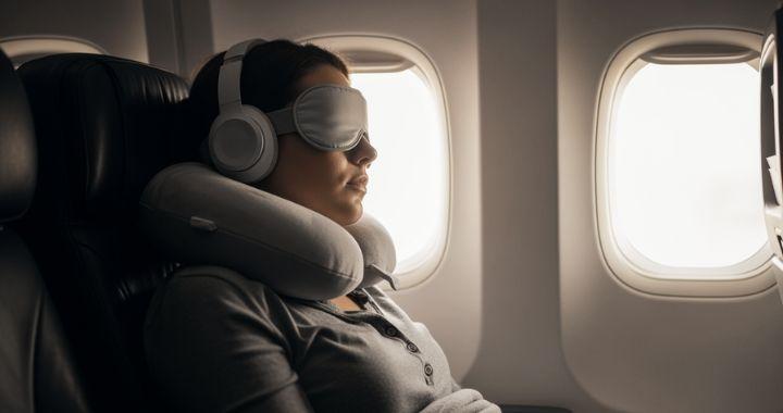 the woman is sleeping with cover on her eyes and with headphone